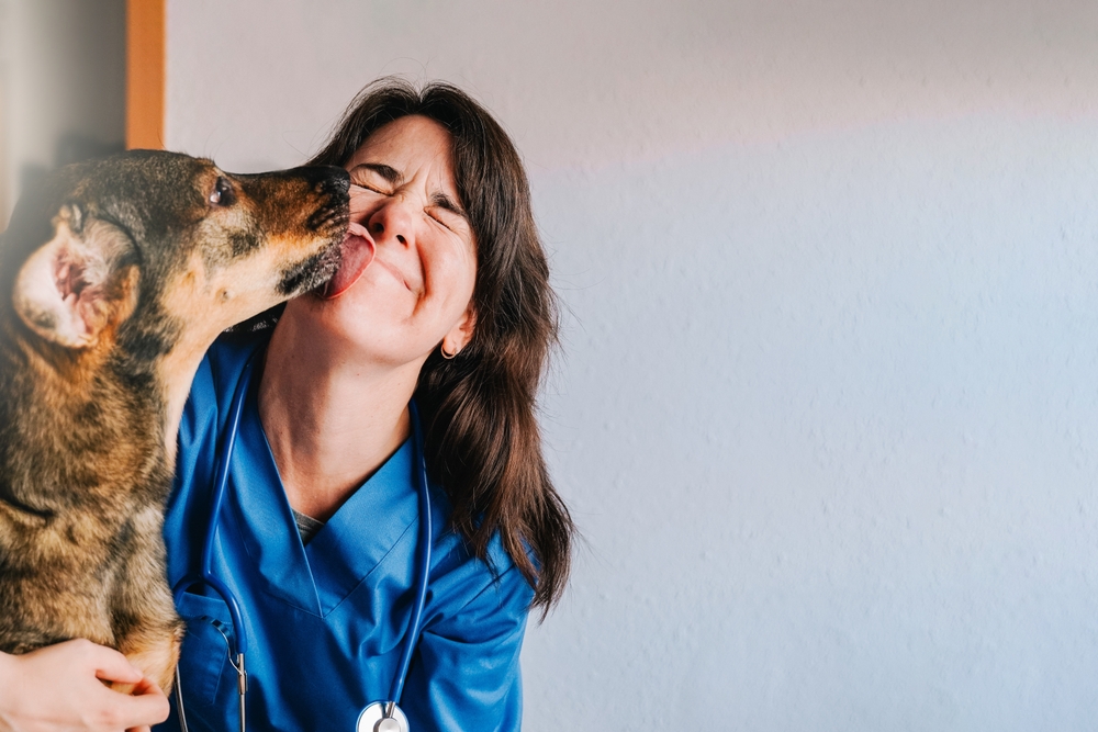 Happy dog licking a smiling veterinarian's face after a checkup at an animal hospital
